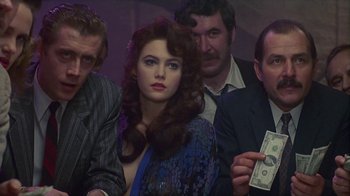 Movie still from “The Big Town” (1987), directed by Harold Becker – A group of men and women sitting around a woman holding money; Close Up shot, Over the shoulder angle