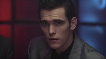 Movie still from “The Big Town” (1987), directed by Harold Becker – A person wearing a suit and tie; Close Up shot, Over the shoulder angle