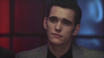 Movie still from “The Big Town” (1987), directed by Harold Becker – A young man in a suit looking to his left; Close Up shot, Over the shoulder angle