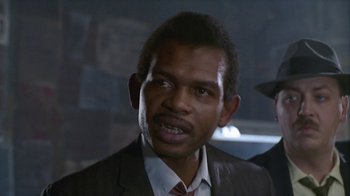 Movie still from “The Big Town” (1987), directed by Harold Becker – A person wearing a suit and tie; Close Up shot, Low angle