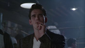 Movie still from “The Big Town” (1987), directed by Harold Becker – A man smoking a cigarette while wearing a suit; Close Up shot, Low angle