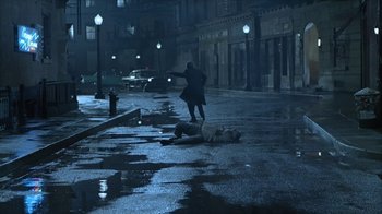 Movie still from “The Big Town” (1987), directed by Harold Becker – A man in a trench coat is standing next to a dead body on the street; Wide shot, High angle