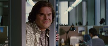 Movie still from “The Big Year” (2011), directed by David Frankel – A man with long brown hair standing next to a window; Close Up shot, Over the shoulder angle