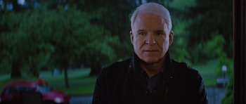 Movie still from “The Big Year” (2011), directed by David Frankel – An older man with white hair is posing for a picture; Close Up shot, Over the shoulder angle