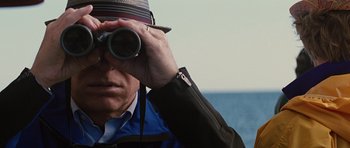Movie still from “The Big Year” (2011), directed by David Frankel – A man looking through binoculars while standing on a boat; Close Up shot, Over the shoulder angle