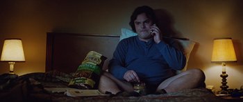 Movie still from “The Big Year” (2011), directed by David Frankel – A man sitting on a bed talking on a phone; Medium shot, Overhead angle