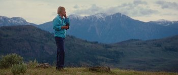 Movie still from “The Big Year” (2011), directed by David Frankel – A woman standing on top of a grass covered hill; Wide shot, Low angle