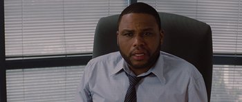 Movie still from “The Big Year” (2011), directed by David Frankel – A man sitting in an office chair wearing a shirt and tie; Close Up shot, Over the shoulder angle