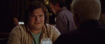 Movie still from “The Big Year” (2011), directed by David Frankel – A man sitting at a table with a glass of wine; Close Up shot, Over the shoulder angle