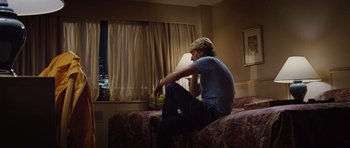 Movie still from “The Big Year” (2011), directed by David Frankel – A man sitting on top of a bed in a hotel room; Medium shot, Over the shoulder angle