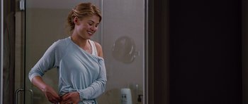 Movie still from “The Big Year” (2011), directed by David Frankel – A woman in a blue shirt is standing in front of a mirror; Medium shot, Over the shoulder angle