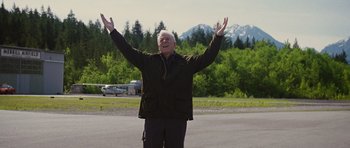 Movie still from “The Big Year” (2011), directed by David Frankel – An older man standing in the middle of the road with his arms outstretched; Medium shot, Low angle