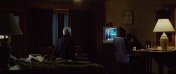 Movie still from “The Big Year” (2011), directed by David Frankel – An older man sitting on a bed in front of a television; Medium shot, High angle