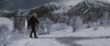 Movie still from “The Big Year” (2011), directed by David Frankel – A man is walking in the snow near a mountain; Wide shot, High angle