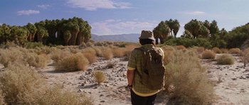 Movie still from “The Big Year” (2011), directed by David Frankel – A man with a backpack walking through a desert; Wide shot, High angle