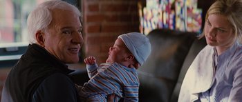 Movie still from “The Big Year” (2011), directed by David Frankel – An older man holding a baby in his arms; Close Up shot, Over the shoulder angle