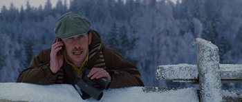 Movie still from “The Big Year” (2011), directed by David Frankel – A man is leaning on the side of a car while holding a video camera; Close Up shot, Low angle