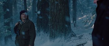 Movie still from “The Big Year” (2011), directed by David Frankel – A person standing next to a tree in the snow; Medium shot, Low angle
