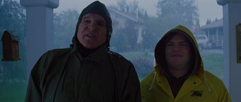 Movie still from “The Big Year” (2011), directed by David Frankel – Two people wearing rain jackets standing in the rain; Medium shot, Low angle