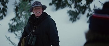 Movie still from “The Big Year” (2011), directed by David Frankel – A man in a hat and a jacket smiles for the camera; Close Up shot, Over the shoulder angle