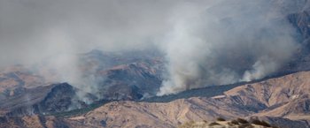 Movie still from “The Biggest Little Farm” (2018), directed by John Chester – Smoke billows from a fire on the side of a mountain; Extreme Wide shot, High angle