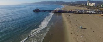 Movie still from “The Biggest Little Farm” (2018), directed by John Chester – An aerial view of a beach with a pier in the background; Extreme Wide shot, High angle