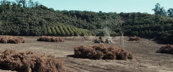 Movie still from “The Biggest Little Farm” (2018), directed by John Chester – A truck driving down a dirt road next to trees; Extreme Wide shot, High angle