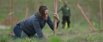 Movie still from “The Biggest Little Farm” (2018), directed by John Chester – A woman kneeling down next to a yellow flag; Medium shot, Over the shoulder angle