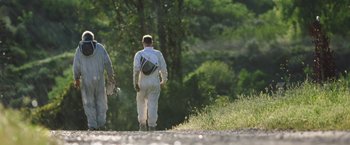 Movie still from “The Biggest Little Farm” (2018), directed by John Chester – Two men in white suits walking down a dirt road; Wide shot, Low angle
