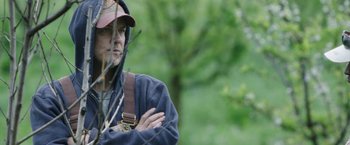 Movie still from “The Biggest Little Farm” (2018), directed by John Chester – A man in a baseball cap is standing in the woods; Close Up shot, Low angle