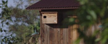 Movie still from “The Biggest Little Farm” (2018), directed by John Chester – A birdhouse on the side of a wooden building; Extreme Close Up shot, Low angle