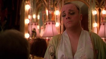 Movie still from “The Birdcage” (1996), directed by Mike Nichols – A man in a robe is sitting in front of lights; Close Up shot, Over the shoulder angle
