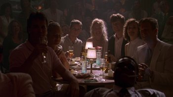 Movie still from “The Birdcage” (1996), directed by Mike Nichols – A group of people sitting around a table with drinks; Medium shot, Low angle