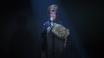Movie still from “The Birdcage” (1996), directed by Mike Nichols – A woman wearing a hat and holding a purse; Medium shot, Over the shoulder angle