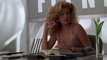 Movie still from “The Birdcage” (1996), directed by Mike Nichols – A woman sitting at a table reading a book; Medium shot, Low angle