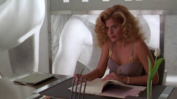 Movie still from “The Birdcage” (1996), directed by Mike Nichols – A woman sitting at a table with a book and a pen; Medium shot, Over the shoulder angle