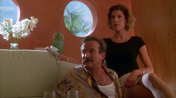 Movie still from “The Birdcage” (1996), directed by Mike Nichols – A man and a woman sitting on a couch in front of a window; Medium shot, Low angle