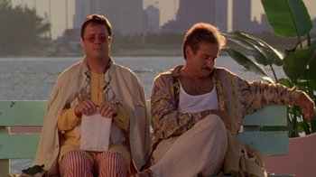 Movie still from “The Birdcage” (1996), directed by Mike Nichols – A couple of men sitting next to each other on top of a bench; Medium shot, Low angle