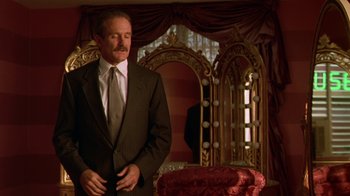 Movie still from “The Birdcage” (1996), directed by Mike Nichols – A man in a suit standing in front of a chair; Medium shot, Low angle