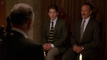 Movie still from “The Birdcage” (1996), directed by Mike Nichols – Two men in suits sitting next to each other in front of candles; Medium shot, Over the shoulder angle