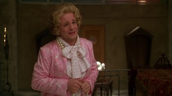 Movie still from “The Birdcage” (1996), directed by Mike Nichols – An older woman wearing a pink suit and a white bow tie; Close Up shot, Over the shoulder angle