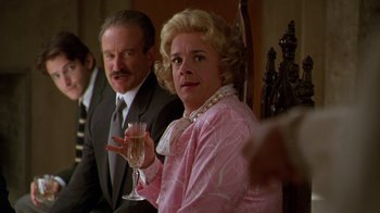Movie still from “The Birdcage” (1996), directed by Mike Nichols – An older woman holding a glass of wine while sitting next to an older man; Close Up shot, Over the shoulder angle