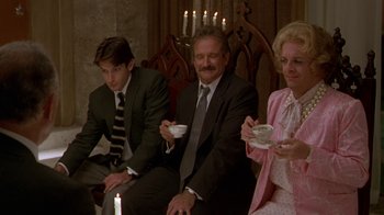 Movie still from “The Birdcage” (1996), directed by Mike Nichols – A man and two women sitting next to each other holding cups; Medium shot, High angle