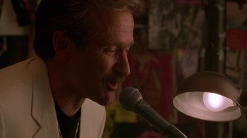 Movie still from “The Birdcage” (1996), directed by Mike Nichols – A person singing on a microphone; Close Up shot, Low angle