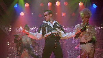 Movie still from “The Birdcage” (1996), directed by Mike Nichols – A man in a black and white outfit on a stage; Medium shot, Low angle