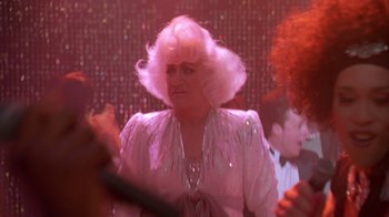 Movie still from “The Birdcage” (1996), directed by Mike Nichols – An older woman in a white dress is dancing in a disco; Close Up shot, Over the shoulder angle