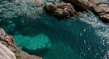 Movie still from “The Black Stallion” (1979), directed by Carroll Ballard – A man is standing on a rock in the water; Extreme Wide shot, Overhead angle