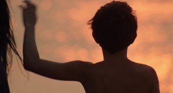 Movie still from “The Black Stallion” (1979), directed by Carroll Ballard – A person with their arms outstretched in front of a sunset; Close Up shot, Low angle