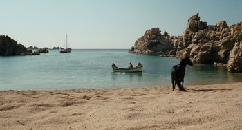 Movie still from “The Black Stallion” (1979), directed by Carroll Ballard – Three people in a boat on a beach with a dog on the shore; Extreme Wide shot, High angle