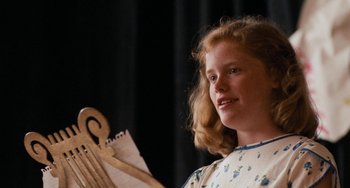Movie still from “The Black Stallion” (1979), directed by Carroll Ballard – A young girl holding a pair of clothes hangers in front of a black background; Close Up shot, Low angle